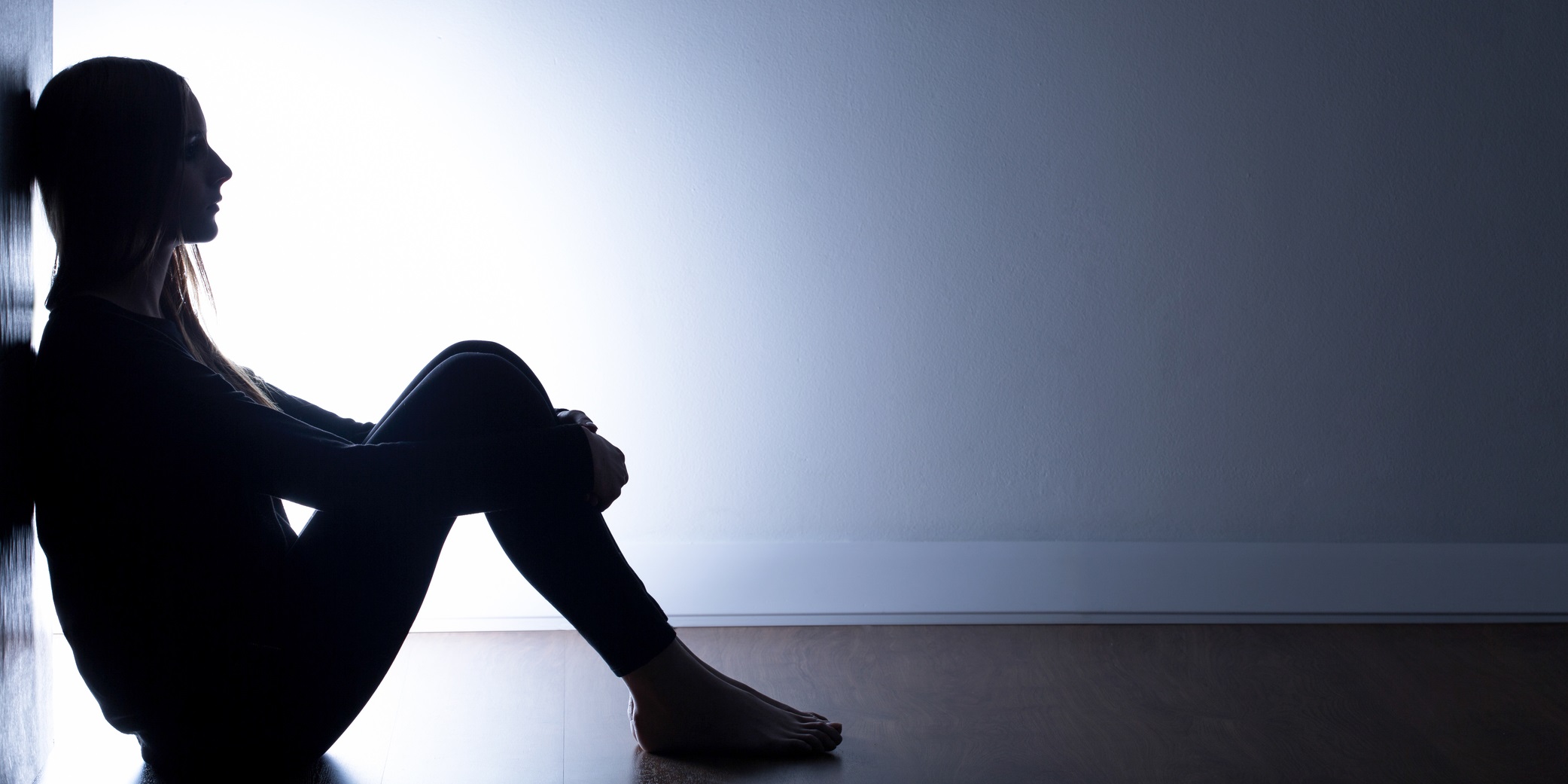 Teenager with depression sitting alone in dark room