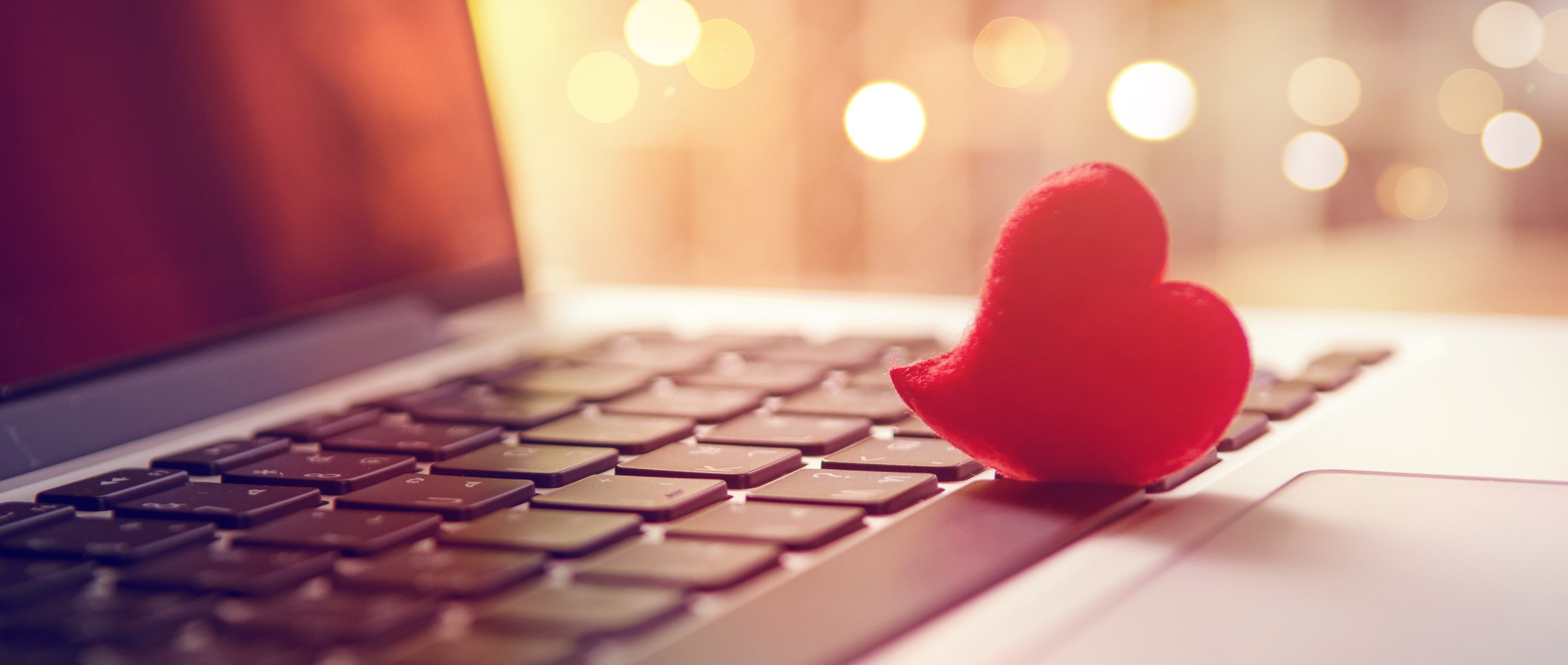 Red heart on the computer keyboard with sunlight and shadow. Internet dating, Valentines day concept.